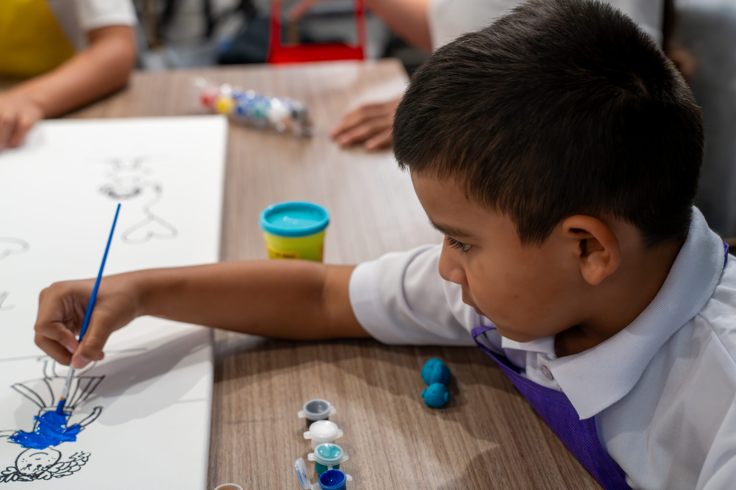 A child painting at a table during an Art & Creativity session at Miami Supreme